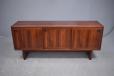 Rosewood short sideboard with 3 sliding doors revealing shelves and drawer storage inside.