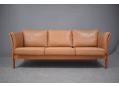 Compact 3 seat box frame sofa in tan leather with cherry frame ends. 