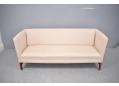 3 seat midcentury design sofa with cream fabric upholstery.
