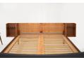 Headboard with side mounted bedside tables each with black glass top.