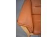 2 seat box design sofa with tan leather upholstered fixed cushions.