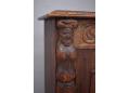 Decoratively carved figures on 1930s dark oak bookcase.