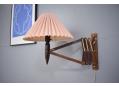 Wall mounted scissor lamp with pink pleated shade.