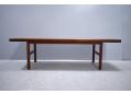 Rectangular coffee table on legs with cross stretchers.