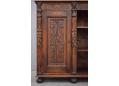 The bookcase features decorative carvings on its cupboard door.